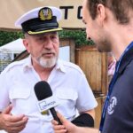 zdjęcie przestawiające mężczyznę w stroju kapitana udzielającego wywiadu młodemu chłopakowi