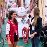 zdjęcie przedstawiające młodą kobietę udzielającą wywiadu na statku, młodej dziennikarce