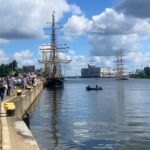 zdjęcie przedstawiające wybrzeże rzeki z zacunowanym statkiem, oraz pływającym pontonem po rzece