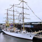 zdjęcie przedstawiające Dar Młodzieży zacumowany przy nabrzeżu nieopodal morskiego centrum nauki