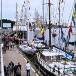 zdjęcie przedstawiające zacumowane łódki oraz spacerujących ludzi po nabrzeżu