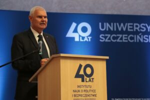Uroczystość 40-lecia Instytutu Nauk o Polityce i Bezpieczeństwie Uniwersytetu Szczecińskiego. Aula. Za mównicą rektor uczelni. W tle fragment granatowej ścianki z napisem: 40 lat Uniwersytetu Szczecińskiego.