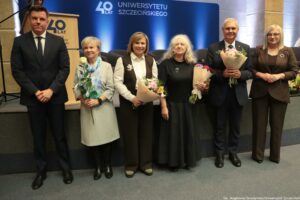 Uroczystość 40-lecia Instytutu Nauk o Polityce i Bezpieczeństwie Uniwersytetu Szczecińskiego. Aula. Przed sceną rektor uczelni i prorektorka (po prawej), dyrektor Instytutu (po lewej) oraz 3 przedstawicielki uczelni z kwiatami (w środku). W tle granatowa ścianka z napisem: 40 lat Uniwersytetu Szczecińskiego.