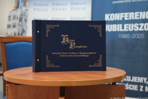 Stojąca na stole granatowa księga pamiątkowa ze złotymi napisami na okładce, powstała z okazji 40-lecia Instytutu Nauk o Polityce i Bezpieczeństwie Uniwersytetu Szczecińskiego.