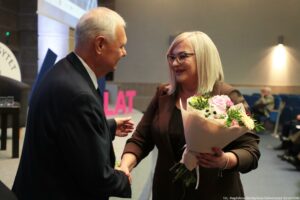 Uroczystość 40-lecia Instytutu Nauk o Polityce i Bezpieczeństwie Uniwersytetu Szczecińskiego. Prorektorka (po prawej) odbiera gratulacje i kwiaty od rektora uczelni.