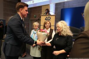 Uroczystość 40-lecia Instytutu Nauk o Polityce i Bezpieczeństwie Uniwersytetu Szczecińskiego. Dziekan jednego z wydziałów (po prawej) odbiera gratulacje i kwiaty od dyrektora instytutu. Po jej prawej stoją dwie inne kobiety.