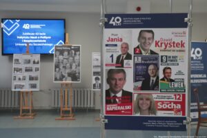 40-lecie Instytutu Nauk o Polityce i Bezpieczeństwie Uniwersytetu Szczecińskiego. Korytarz. Po prawej fragment wystawy plansz z plakatami i ulotkami wyborczymi absolwentów uczelni. W tle wystawa nawiązująca do historii Instytutu.
