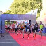 Start biegaczy 46. PKO Półmaratonu Szczecin. Po bokach granatowe barierki z białymi napisami Szczecin. W tle drzewa.
