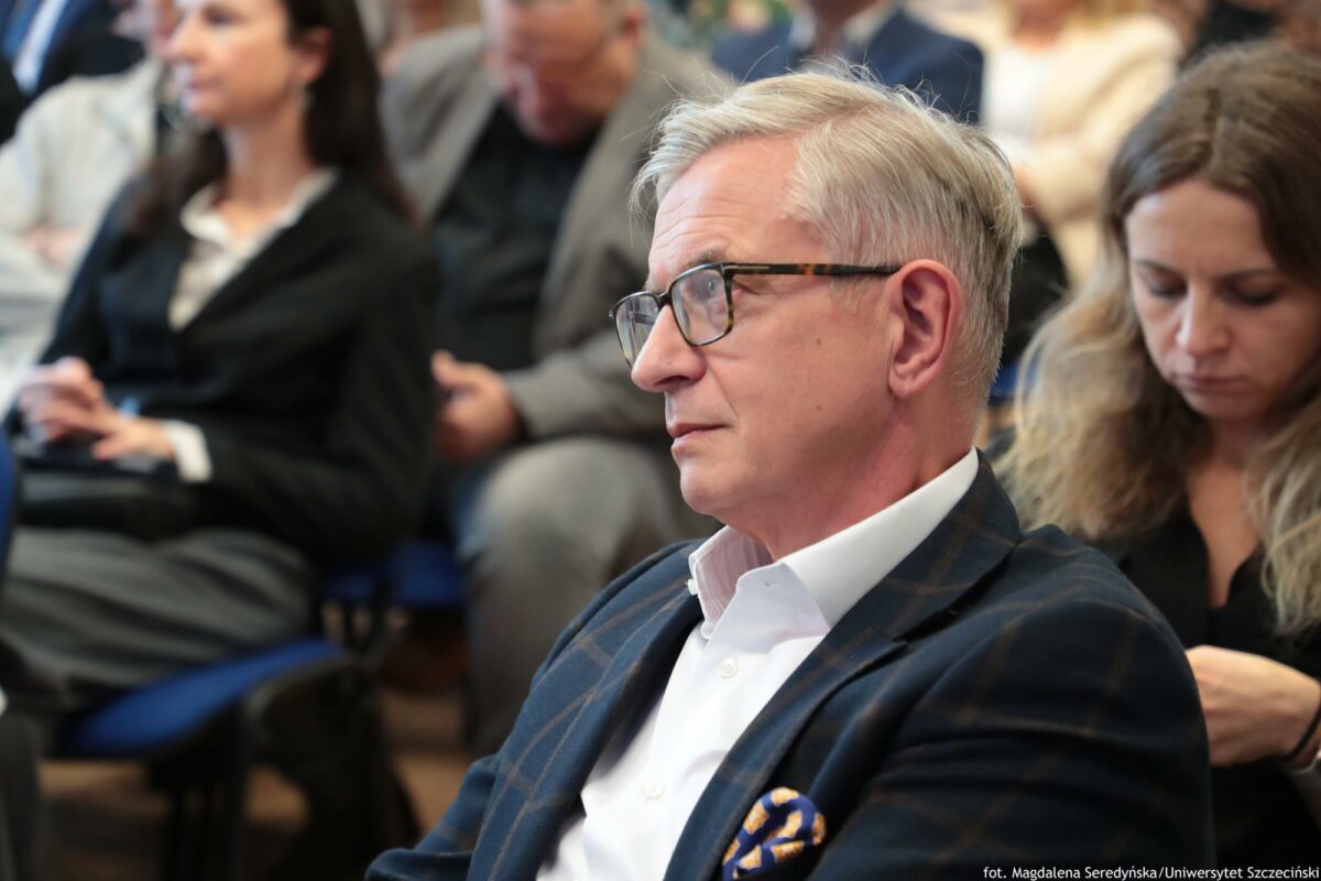 Prelegent siedzący wśród słuchaczy na konferencji (ujęcie do pasa – bokiem).