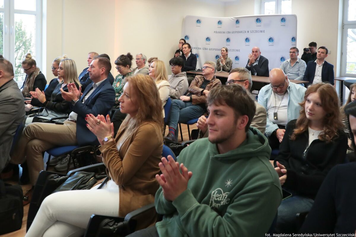 Słuchacze konferencji o AI klaszczą po zakończeniu wykładów (ujęcie bokiem).