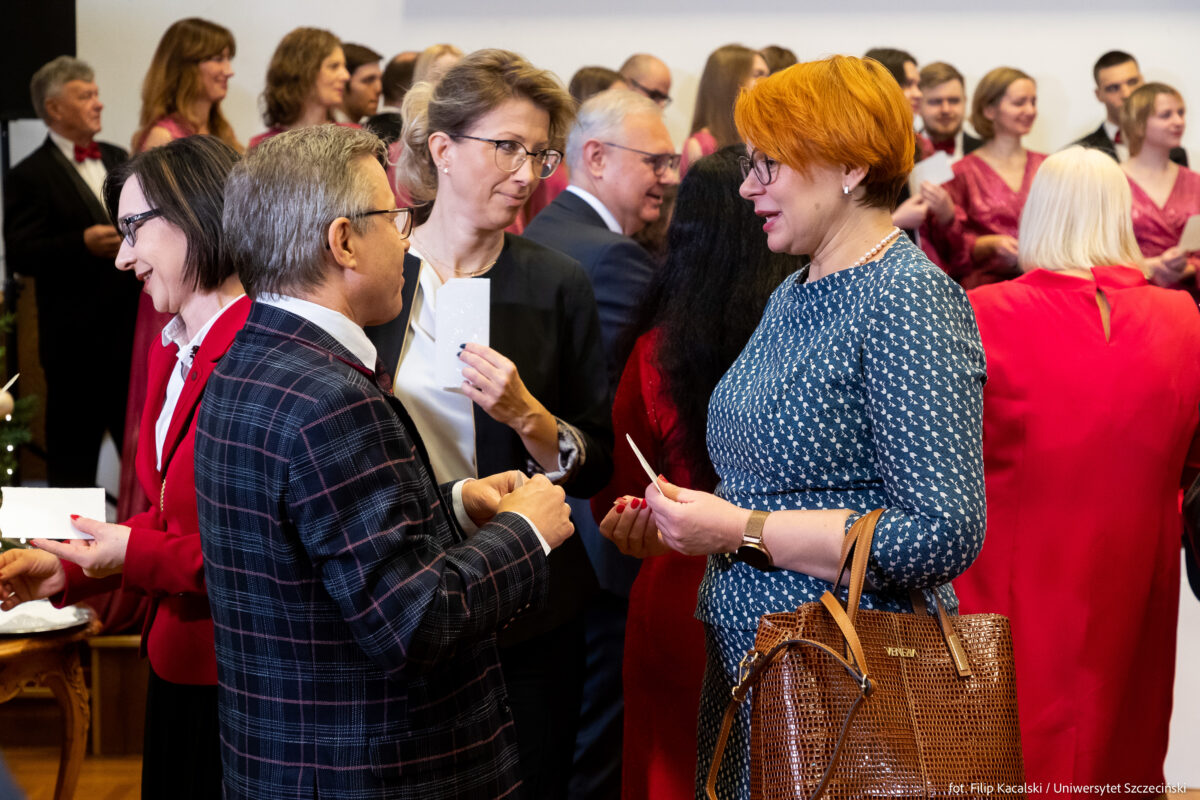 Uczestnicy spotkania wigilijnego przełamują się opłatkiem. 