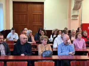Sala Wydziału Ekonomii, Finansów i Zarządzania. Ujęcie bokiem. Około 20-osobowa grupa uczestników siedzi na krzesłach podczas otwarcia uroczystości zakończenia 40-lecia Uniwersytetu Szczecińskiego.
