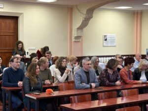Sala Wydziału Ekonomii, Finansów i Zarządzania. Ujęcie bokiem. Ponad 20-osobowa grupa uczestników siedzi na krzesłach podczas otwarcia uroczystości zakończenia 40-lecia Uniwersytetu Szczecińskiego.