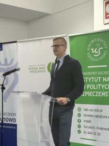 zdjęcie jednego z przemawiających prelegentów ( mężczyzna stojący przy mównicy z mikrofonem)