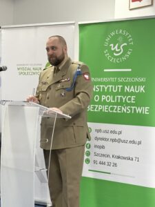 zdjęcie jednego z przemawiających prelegentów ( mężczyzna w mundurze stojący przy mównicy z mikrofonem)
