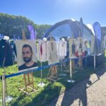 Stojące na sztalugach w plenerze zdjęcia utytułowanych sportowców z Uniwersytetu Szczecińskiego i postawione obok nich stroje olimpijskie, stanowiące zasoby Muzeum Olimpizmu Uniwersytetu Szczecińskiego.