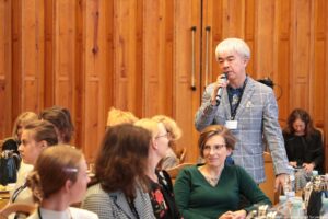 Siedzący przy stołach uczestnicy III Międzynarodowego Kongresu Języka i Kultury Polskiej (kadr na 10 osób). Po prawej stojący z mikrofonem prelegent, zadający pytanie podczas dyskusji.