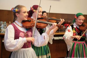 Zespół Pieśni i Tańca Szczecinianie. Trzy kobiety ubrane w stroje ludowe i grające na skrzypcach.