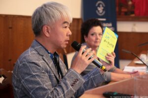 III Międzynarodowy Kongres Języka i Kultury Polskiej. Ujęcie bokiem. Na pierwszym planie prof. Koji Morita (Japonia), który pokazuje podręcznik do nauki języka polskiego, obok niego prof. Ewa Kołodziejek (US).