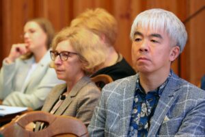 Siedzący przy stołach (ujęcie na 4 osoby) uczestnicy III Międzynarodowego Kongresu Języka i Kultury Polskiej. Na pierwszym planie (po prawej) prelegent z Japonii, słuchający wykładu.