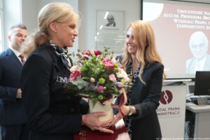Uroczystość nadania auli im. Profesora Bronisława Ziemianina – Wydział Prawa i Administracji Uniwersytetu Szczecińskiego. Dziekan Wydziału dr hab. Ewelina Cała-Wacinkiewicz, prof. US (po prawej, bokiem) wręcza kwiaty krewnej pana profesora. W tle odsłonięta tablica.