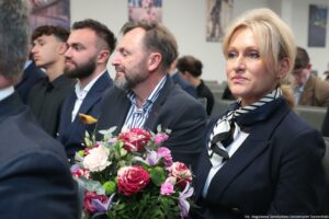 Uroczystość nadania auli im. Profesora Bronisława Ziemianina – Wydział Prawa i Administracji Uniwersytetu Szczecińskiego. Ujęcie bokiem na ludzi siedzących w rzędach w sali. Na pierwszym planie kobieta z kwiatami – krewna profesora.