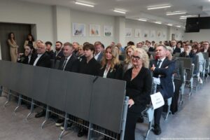 Otwarcie budynku Wydziału Prawa i Administracji Uniwersytetu Szczecińskiego. Ujęcie bokiem na ludzi siedzących w rzędach w sali.