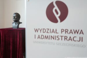 Po prawej bordowy napis Wydział Prawa i Administracji Uniwersytetu Szczecińskiego na białym tle. Po lewej popiersie mężczyzny ustawione na bordowym welurze.
