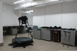 Otwarcie budynku Wydziału Prawa i Administracji Uniwersytetu Szczecińskiego. Sala symulacji. Na metalowych szafkach pod ścianą leżą kamizelki i inne elementy z obciążnikami. O szafki oparte są dwie laski.