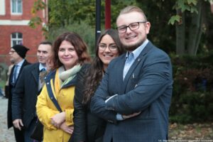 Otwarcie budynku Wydziału Prawa i Administracji Uniwersytetu Szczecińskiego. Ludzie zgromadzeni przed wejściem. Na pierwszym planie 3 osoby.