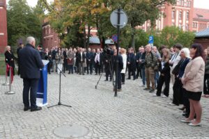 Otwarcie budynku Wydziału Prawa i Administracji Uniwersytetu Szczecińskiego. Ludzie zgromadzeni przed wejściem (przodem i bokiem do kadru). Rektor US za mównicą (tyłem do kadru).