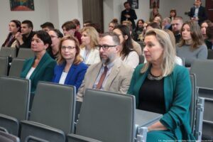 Otwarcie budynku Wydziału Prawa i Administracji Uniwersytetu Szczecińskiego. Ujęcie bokiem. Uczestnicy siedzący w rzędach w sali.