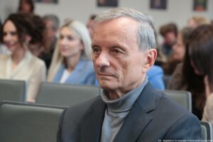 Otwarcie budynku Wydziału Prawa i Administracji Uniwersytetu Szczecińskiego. Ujęcie bokiem na ludzi siedzących w rzędach w sali. Na pierwszym planie prof. dr hab. Marek Górski.