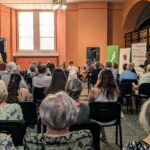 zdjęcie przedstawiające grającego na gitarze mężczyznę się mężczyznę, oraz część wsłuchanej publiczności