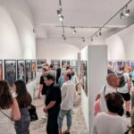 zdjęcie przedstawiające ludzi oglądających wywieszoną na ścianach wystawę
