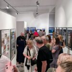 zdjęcie przedstawiające ludzi oglądających wywieszoną na ścianach wystawę