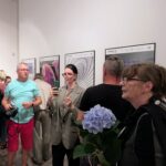 zdjęcie przedstawiające ludzi oglądających wywieszoną na ścianach wystawę