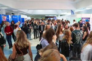 Kilkudziesięcioosobowa grupa uczniów na korytarzu podczas Szczecińskiego Salonu Maturzystów. Po bokach stoiska uczelni z całej Polski.