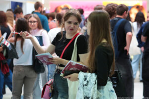 Dwie uczennice trzymające informatory podczas Szczecińskiego Salonu Maturzystów – jedna przodem, druga bokiem. W tle inni uczestnicy wydarzenia.