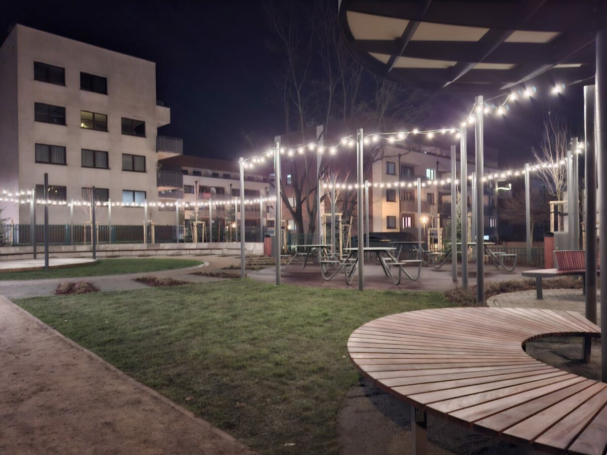 Ujęcie nocą na Piastów Chill Garden, czyli strefę relaksu, która powstała na terenie Uniwersytetu Szczecińskiego. Na zdjęciu ławki z krzesłami, nasadzenia i zawieszone u góry świecące lampki.