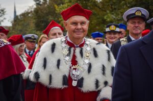 Spacerek na uniwerek. Na pierwszym planie rektor Uniwersytetu Szczecińskiego w czerwonej todze z gronostajami. W tle prorektorki US oraz władze innych uczelni w togach i mundurach.