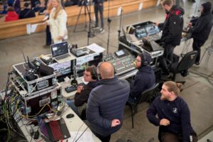 Ujęcie od góry. Ekipa Uniwizji – Telewizji Uniwersytetu Szczecińskiego realizuje transmisję na żywo w inauguracji w Teatrze Letnim. Kilku mężczyzn s(tyłem do kadru) siedzi za ekranami i konsolami transmisyjnymi.
