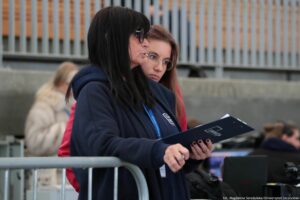 Ujęcie bokiem. Beata Mikołajewska-Wieczorek – dyrektorka Centrum Edukacji Medialnej i Interaktywności ze stojącą za nią członkinią jej zespołu podczas realizacji transmisji z inauguracji.