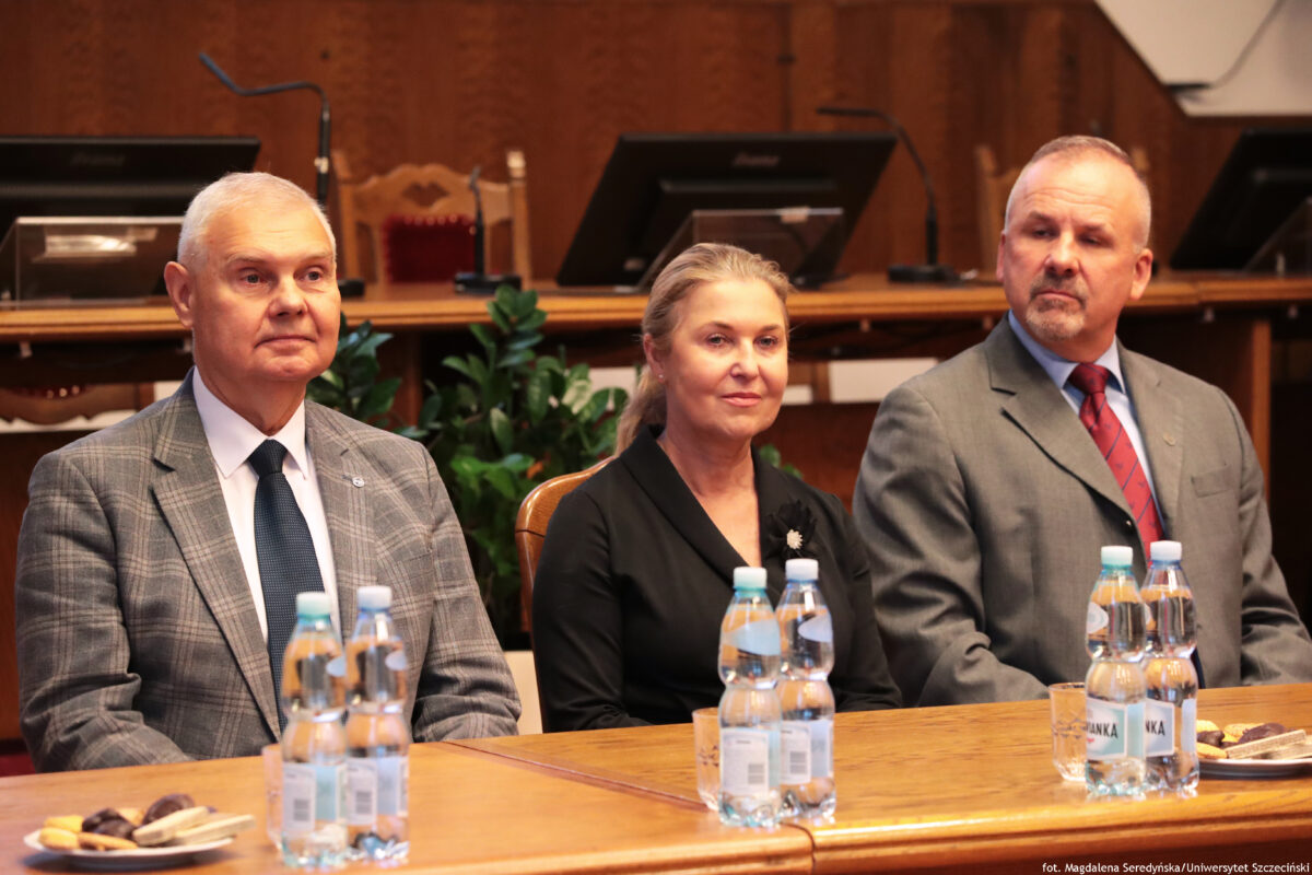 zdjęcie przedstawiające trzy osoby, dwóch mężczyzn oraz kobietę siedzących przy stole prezydialnym