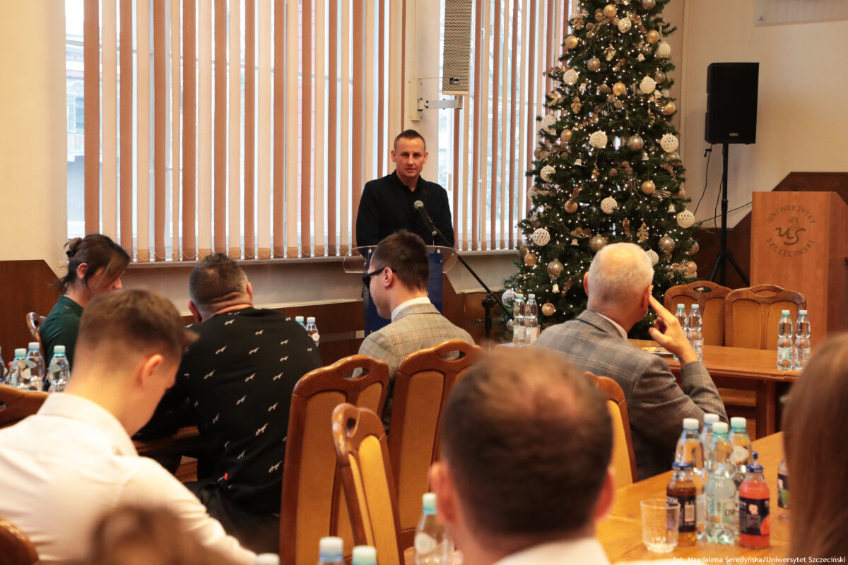 zdjęcie grupy ludzi siędzących w sali senatu podczas spotkania, jeden z mężczyzn stojący przy mównicy