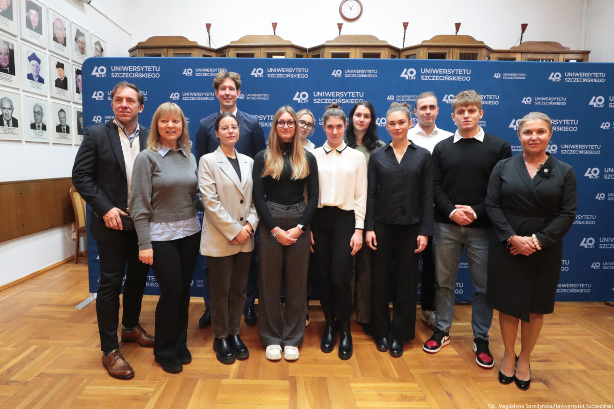 zdjęcie przedstawiające grupę ludzi pozujących na ściance US