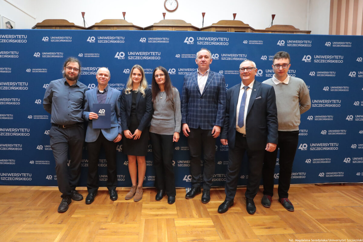 zdjęcie przedstawiające grupę ludzi pozujących na ściance US