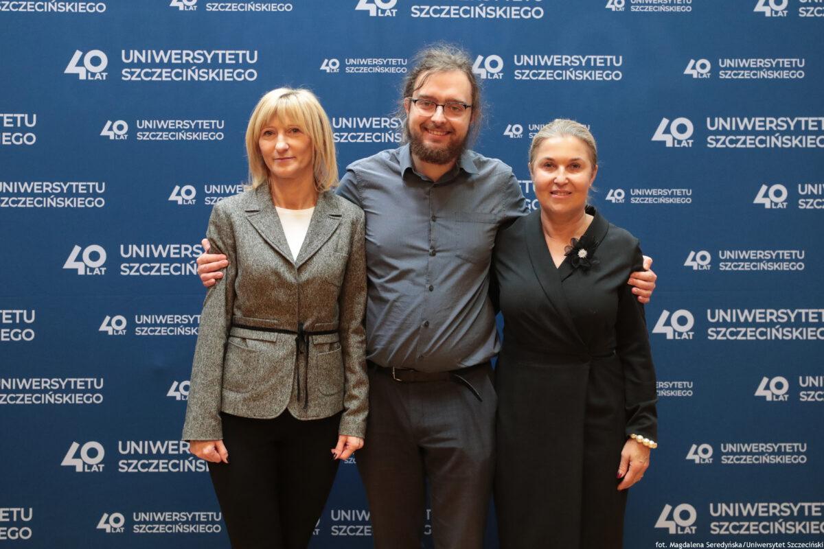 zdjęcie przedstawiające dwie kobiety oraz mężczyznę pozujących na ściance US