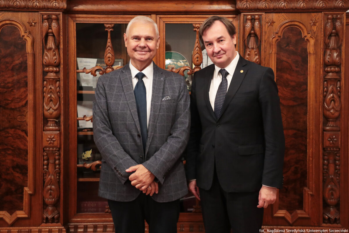 Rektor Uniwersytetu Szczecińskiego – prof. Waldemar Tarczyński i Rektor Uniwersytetu Wileńskiego – prof. dr Rimvydas Petrauskas pozują do zdjęcia na tle zabytkowej, drewnianej szafy (ujęcie do kolan).