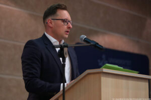 Aula. Za mównicą wykładowca. Po lewej mikrofon na statywie.